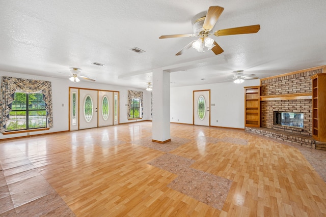 unfurnished living room featuring plenty of natural light, a brick fireplace, and a textured ceiling