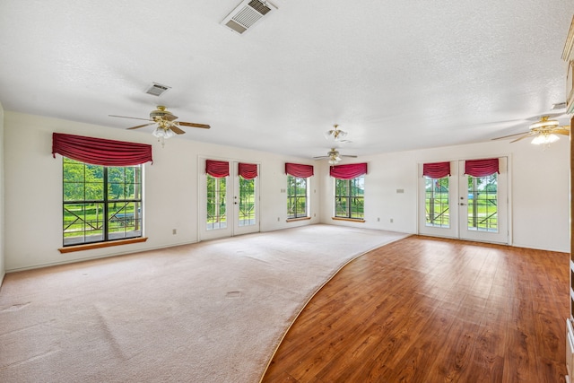 unfurnished living room featuring hardwood / wood-style floors, french doors, and a textured ceiling