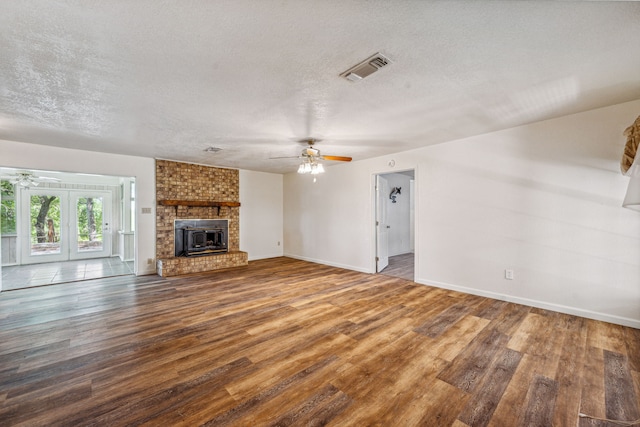 unfurnished living room with hardwood / wood-style floors, ceiling fan, a fireplace, and a textured ceiling