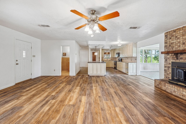 unfurnished living room featuring wood-type flooring, ceiling fan, a textured ceiling, and a fireplace