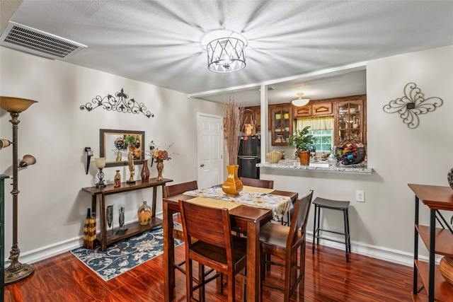 dining space with dark wood-type flooring, a textured ceiling, and a chandelier