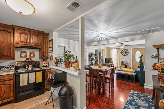 kitchen with wood-type flooring, electric range, light stone counters, and ceiling fan