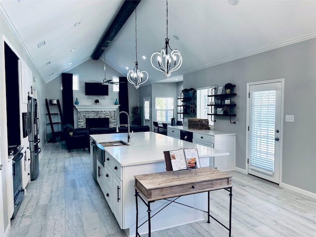 kitchen with white cabinetry, a kitchen island with sink, and a brick fireplace