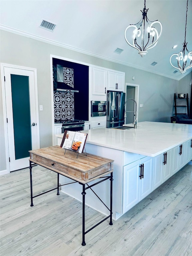 kitchen with white cabinetry, sink, stainless steel appliances, a chandelier, and pendant lighting