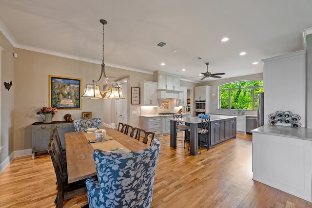 dining room featuring ceiling fan with notable chandelier, sink, light hardwood / wood-style flooring, and ornamental molding