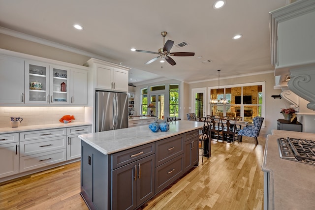 kitchen with appliances with stainless steel finishes, decorative light fixtures, light hardwood / wood-style flooring, and white cabinets