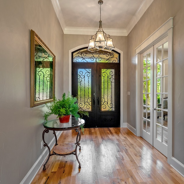 entrance foyer with ornamental molding, hardwood / wood-style flooring, and french doors