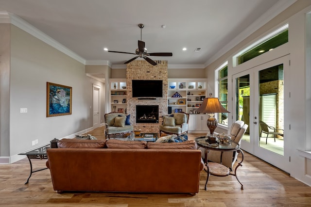 living room with ceiling fan, french doors, light hardwood / wood-style floors, a fireplace, and ornamental molding