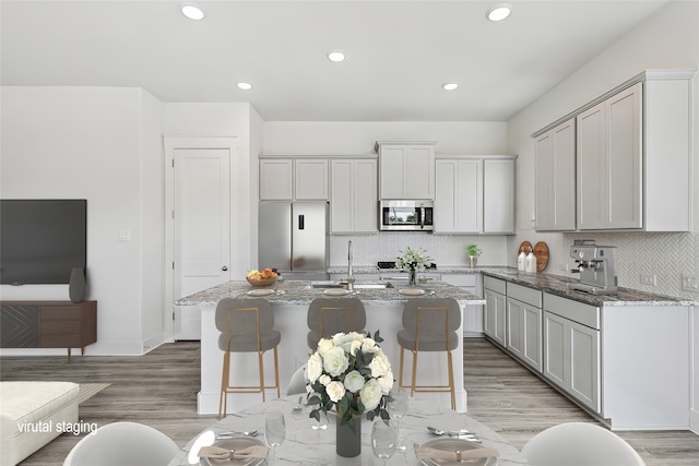 kitchen featuring an island with sink, appliances with stainless steel finishes, and light hardwood / wood-style flooring