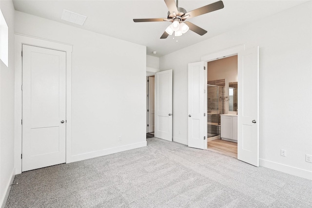 unfurnished bedroom featuring ceiling fan, ensuite bathroom, and light colored carpet