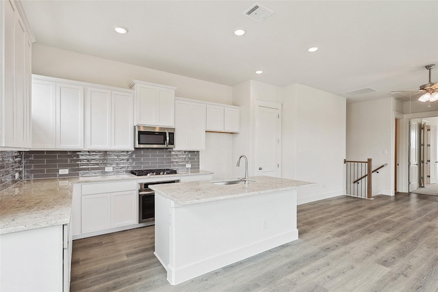 kitchen with white cabinetry, sink, stainless steel appliances, and an island with sink