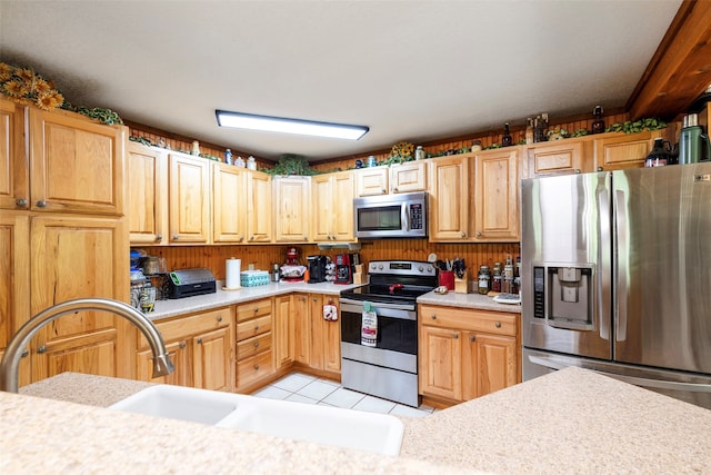 kitchen featuring appliances with stainless steel finishes, sink, and light tile flooring