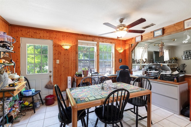 dining space with plenty of natural light, ceiling fan, light tile floors, and wooden walls