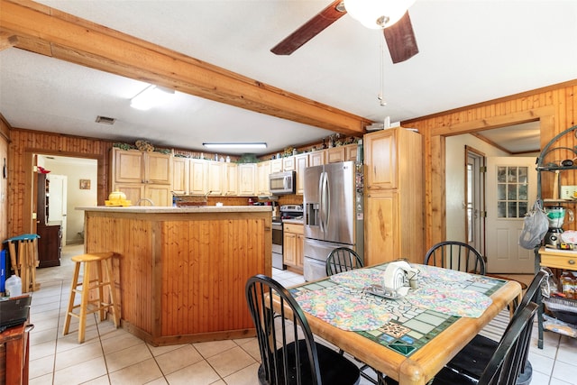 kitchen with appliances with stainless steel finishes, ceiling fan, light tile floors, a breakfast bar area, and ornamental molding