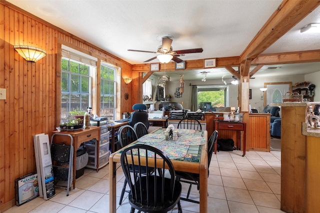 dining space with wood walls, ceiling fan, and light tile floors