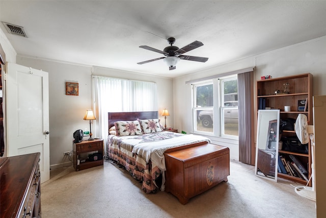 bedroom with ceiling fan, light carpet, and ornamental molding