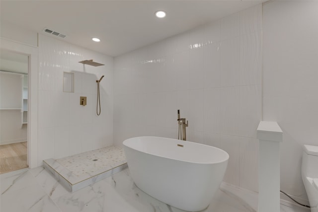 bathroom featuring tile walls and separate shower and tub