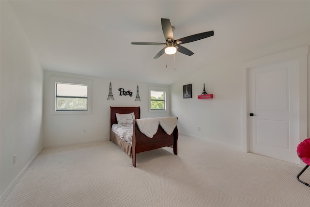 bedroom with ceiling fan, light colored carpet, and multiple windows