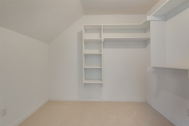 walk in closet with light colored carpet and lofted ceiling