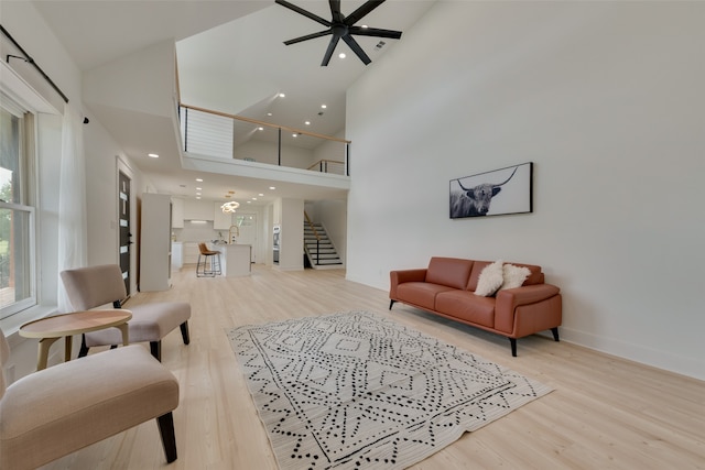 living room featuring ceiling fan, hardwood / wood-style floors, and a high ceiling