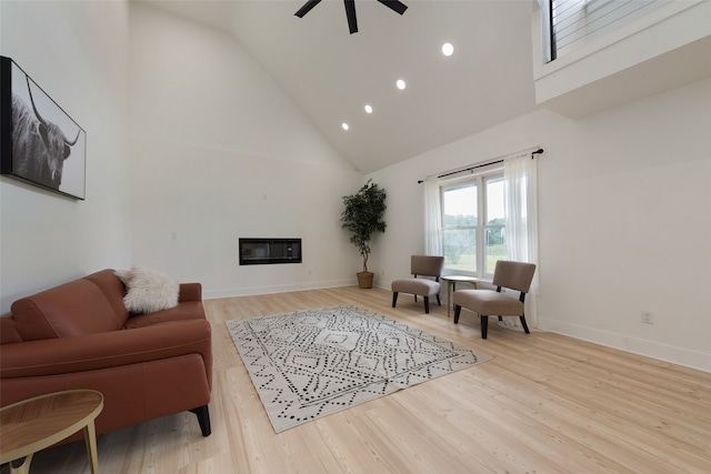 living room with ceiling fan, light hardwood / wood-style flooring, and high vaulted ceiling