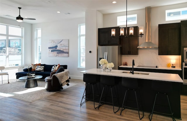 kitchen with backsplash, sink, hanging light fixtures, a kitchen island with sink, and stainless steel appliances