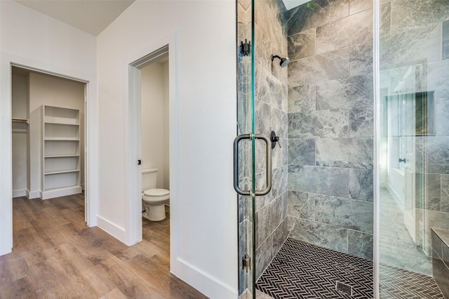 bathroom with toilet, wood-type flooring, and an enclosed shower