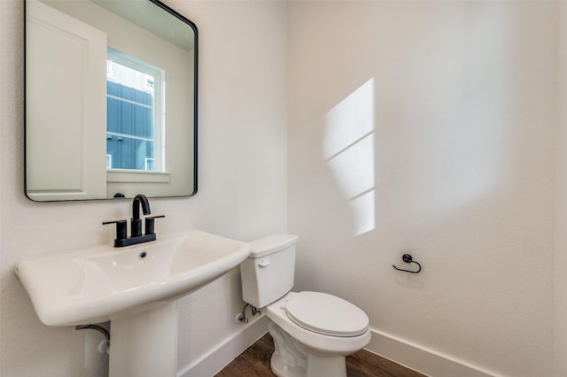 bathroom with toilet, wood-type flooring, and sink