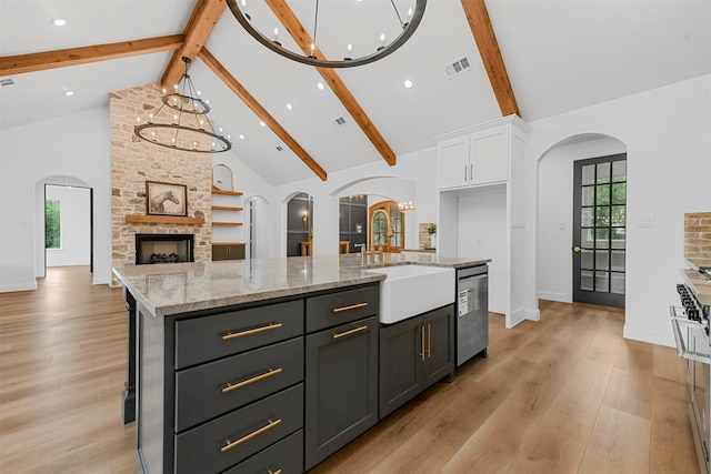 kitchen with high vaulted ceiling, white cabinets, sink, an island with sink, and stainless steel appliances