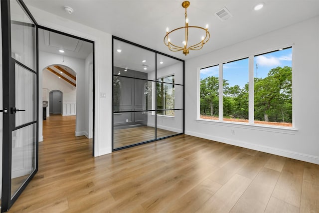 spare room with beam ceiling, light hardwood / wood-style flooring, and a chandelier