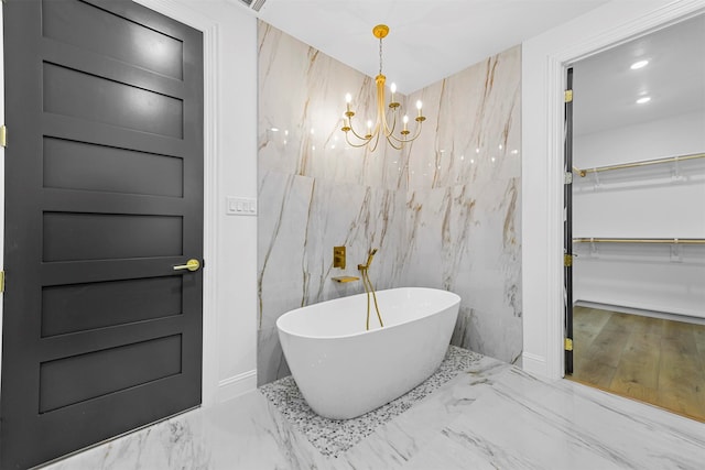 bathroom featuring tile walls, a bath, and a chandelier