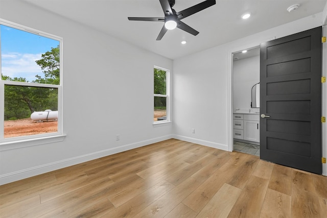 unfurnished bedroom featuring ceiling fan, light wood-type flooring, and ensuite bath