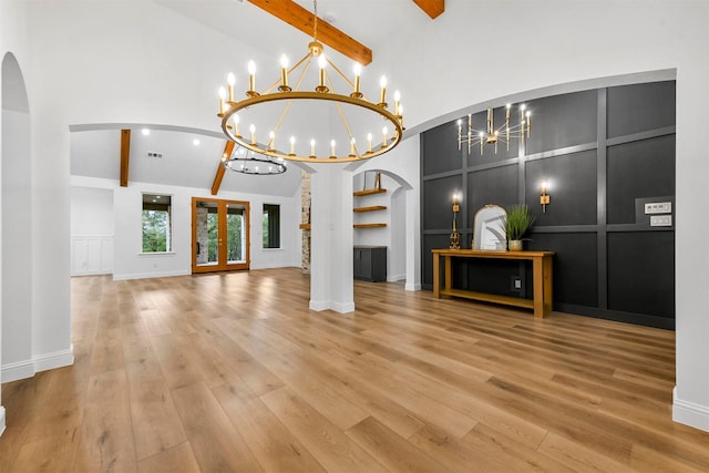 unfurnished living room featuring high vaulted ceiling, built in features, a notable chandelier, beamed ceiling, and hardwood / wood-style floors