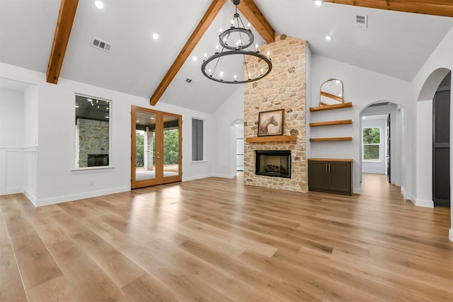 unfurnished living room featuring a fireplace, light hardwood / wood-style flooring, high vaulted ceiling, and a chandelier