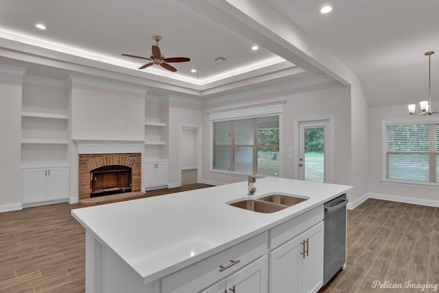 kitchen featuring light hardwood / wood-style floors, ceiling fan with notable chandelier, a kitchen island with sink, sink, and stainless steel dishwasher