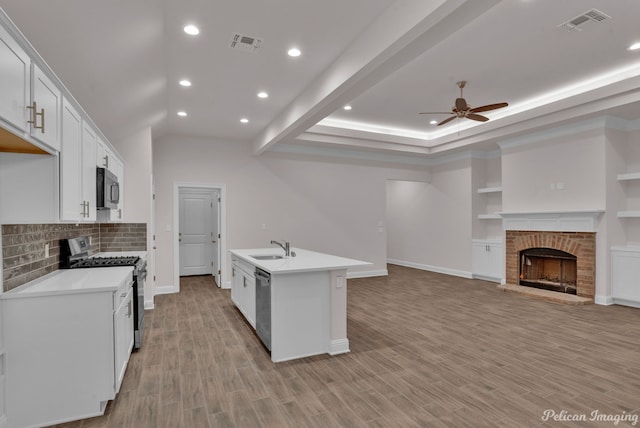 kitchen featuring a kitchen island with sink, light wood-type flooring, white cabinetry, appliances with stainless steel finishes, and ceiling fan