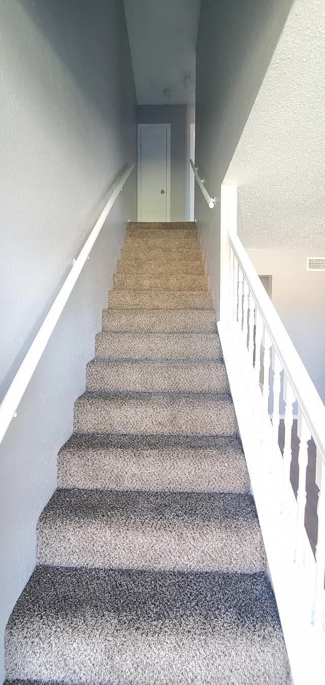 stairway with carpet and a textured ceiling