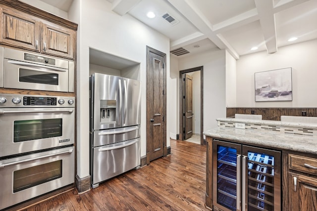 kitchen with beverage cooler, beamed ceiling, appliances with stainless steel finishes, dark hardwood / wood-style flooring, and coffered ceiling