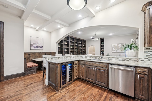 kitchen featuring light stone countertops, kitchen peninsula, stainless steel dishwasher, sink, and wine cooler