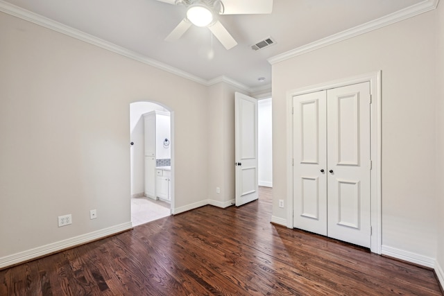 unfurnished bedroom with ensuite bath, ceiling fan, dark hardwood / wood-style floors, and ornamental molding