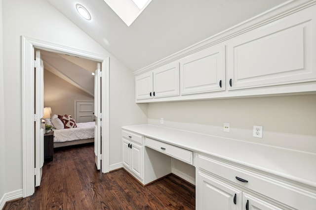 office with built in desk, lofted ceiling with skylight, and dark wood-type flooring