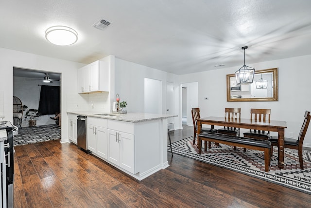 kitchen with light stone counters, white cabinets, sink, ceiling fan with notable chandelier, and dark hardwood / wood-style floors