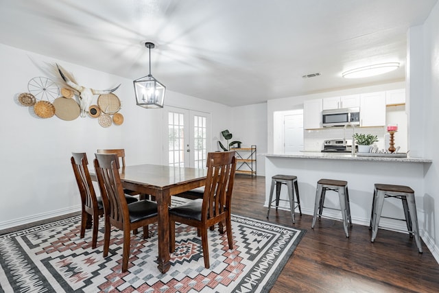 dining area featuring french doors, dark wood-type flooring, and a notable chandelier