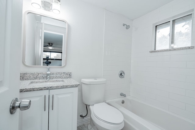 full bathroom with vanity with extensive cabinet space, a healthy amount of sunlight, tiled shower / bath, and toilet