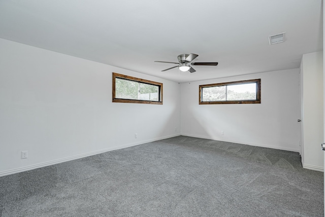 empty room with dark colored carpet and ceiling fan