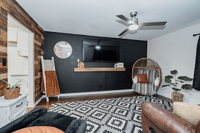 living room featuring hardwood / wood-style floors, ceiling fan, and wooden walls