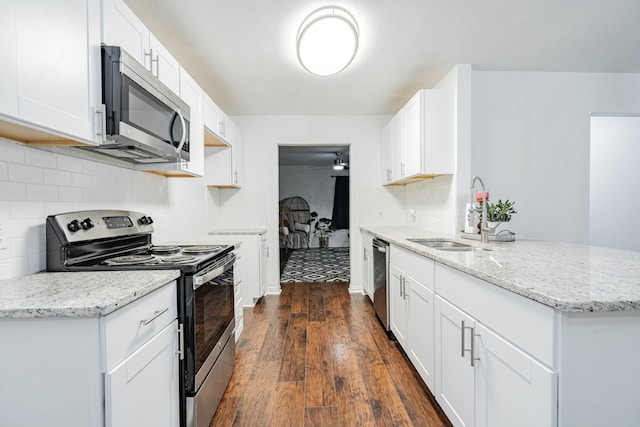 kitchen with appliances with stainless steel finishes, dark hardwood / wood-style floors, tasteful backsplash, white cabinets, and sink