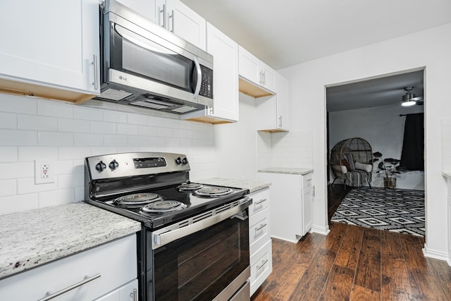 kitchen with white cabinetry, appliances with stainless steel finishes, tasteful backsplash, light stone counters, and dark hardwood / wood-style flooring