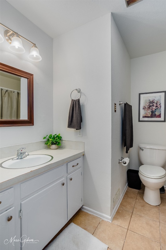 bathroom with toilet, tile flooring, and vanity