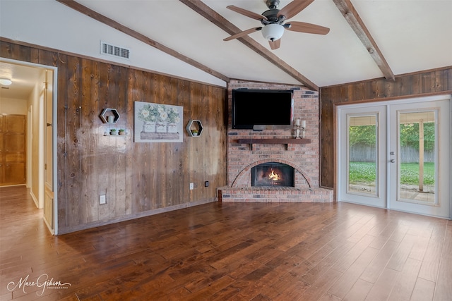 unfurnished living room with wood walls, hardwood / wood-style floors, and vaulted ceiling with beams